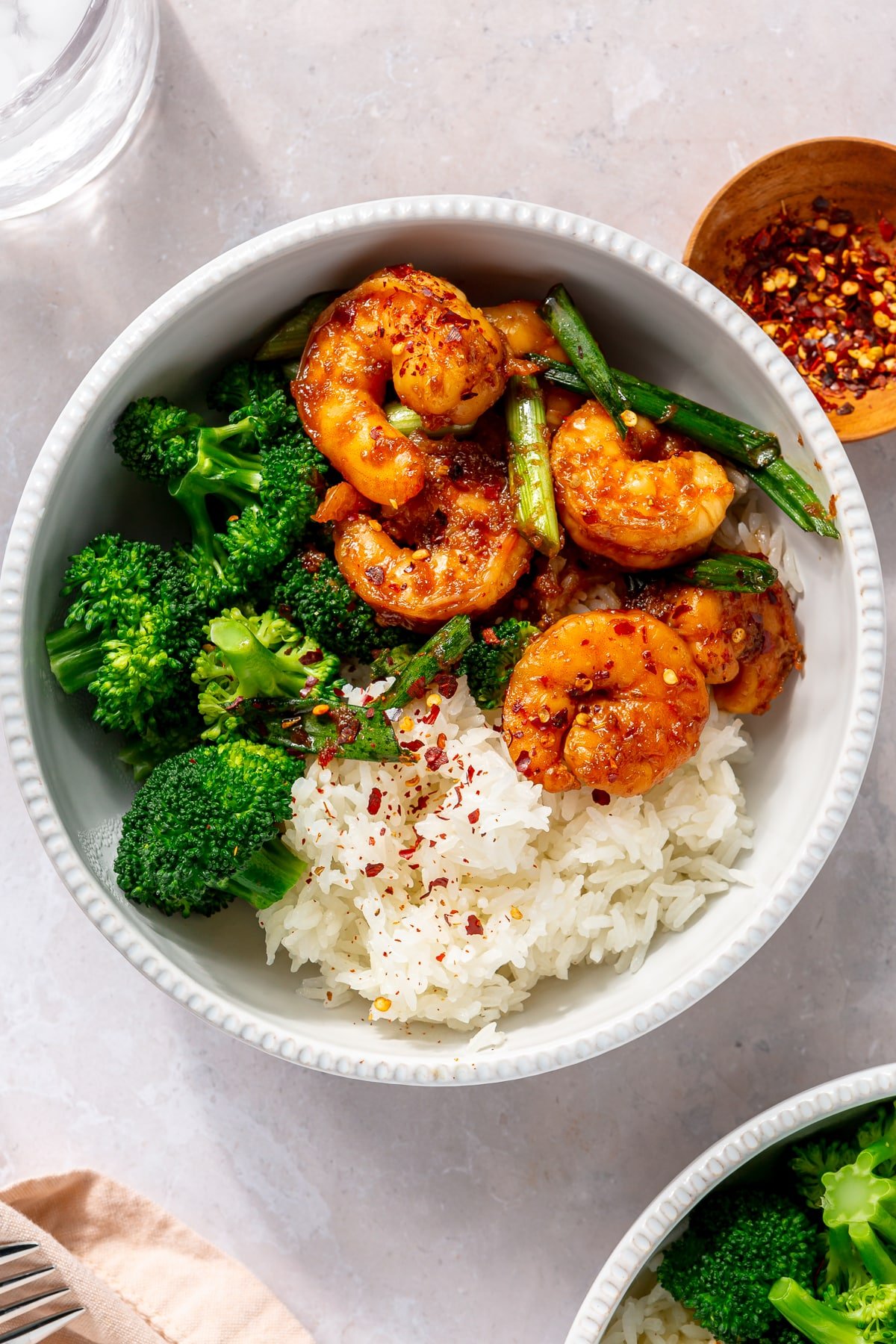 A white bowl filled with white rice, steamed broccoli, and honey garlic shrimp.