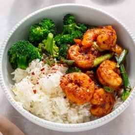 A white bowl filled with white rice, steamed broccoli, and honey garlic shrimp.