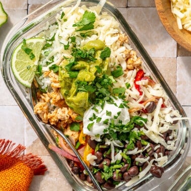 A fully prepared turkey burrito bowl sits on a white tiled surface.