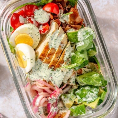 Green goddess salad sits in a glass storage container.