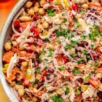 Complete grinder salad sits in a large grey colored serving bowl. Shredded parmesan has been sprinkled over the top.