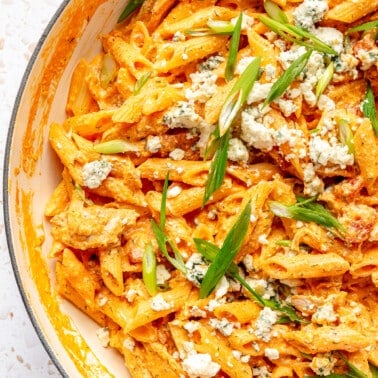 Creamy buffalo chicken pasta in a white enameled pot.