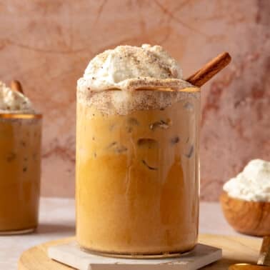 A coffee beverage, made with gingerbread creamer, sits in a glass with a gold rim.