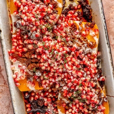 Stuffed butternut squash has been topped with pomegranate seeds.