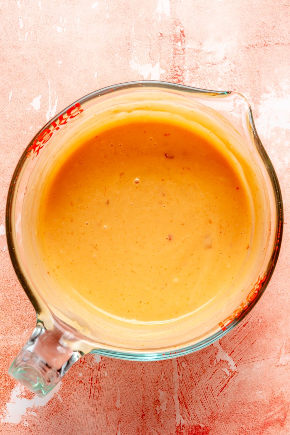 Bang bang sauce in a glass measuring cup.