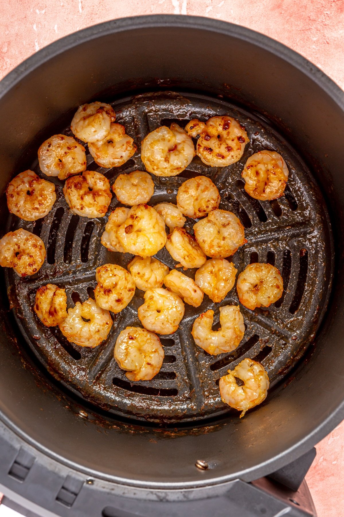 Cooked bang bang shrimp in the basket of an air fryer.