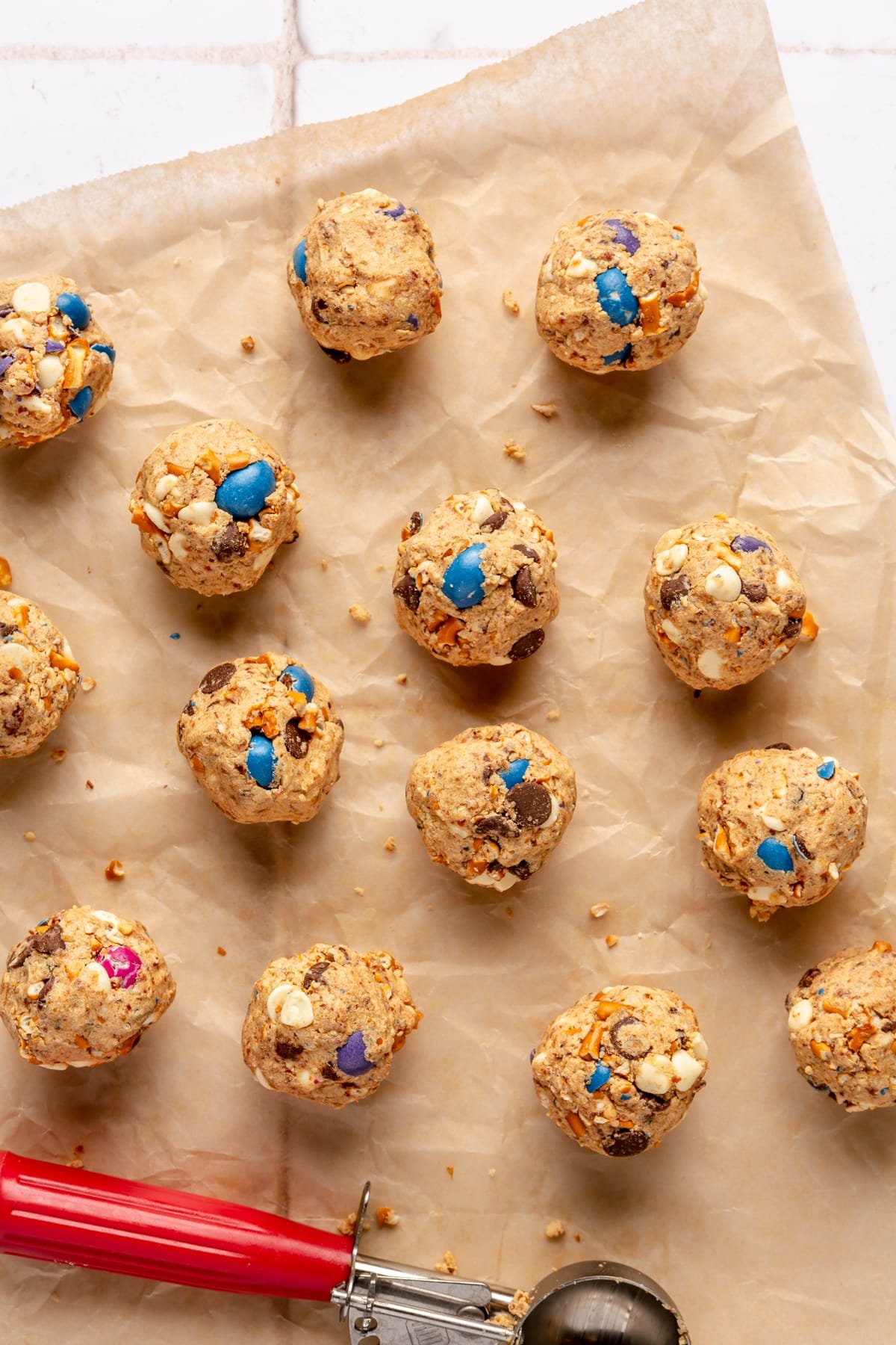 Kitchen Sink energy balls on parchment paper next to a cookie scooper.