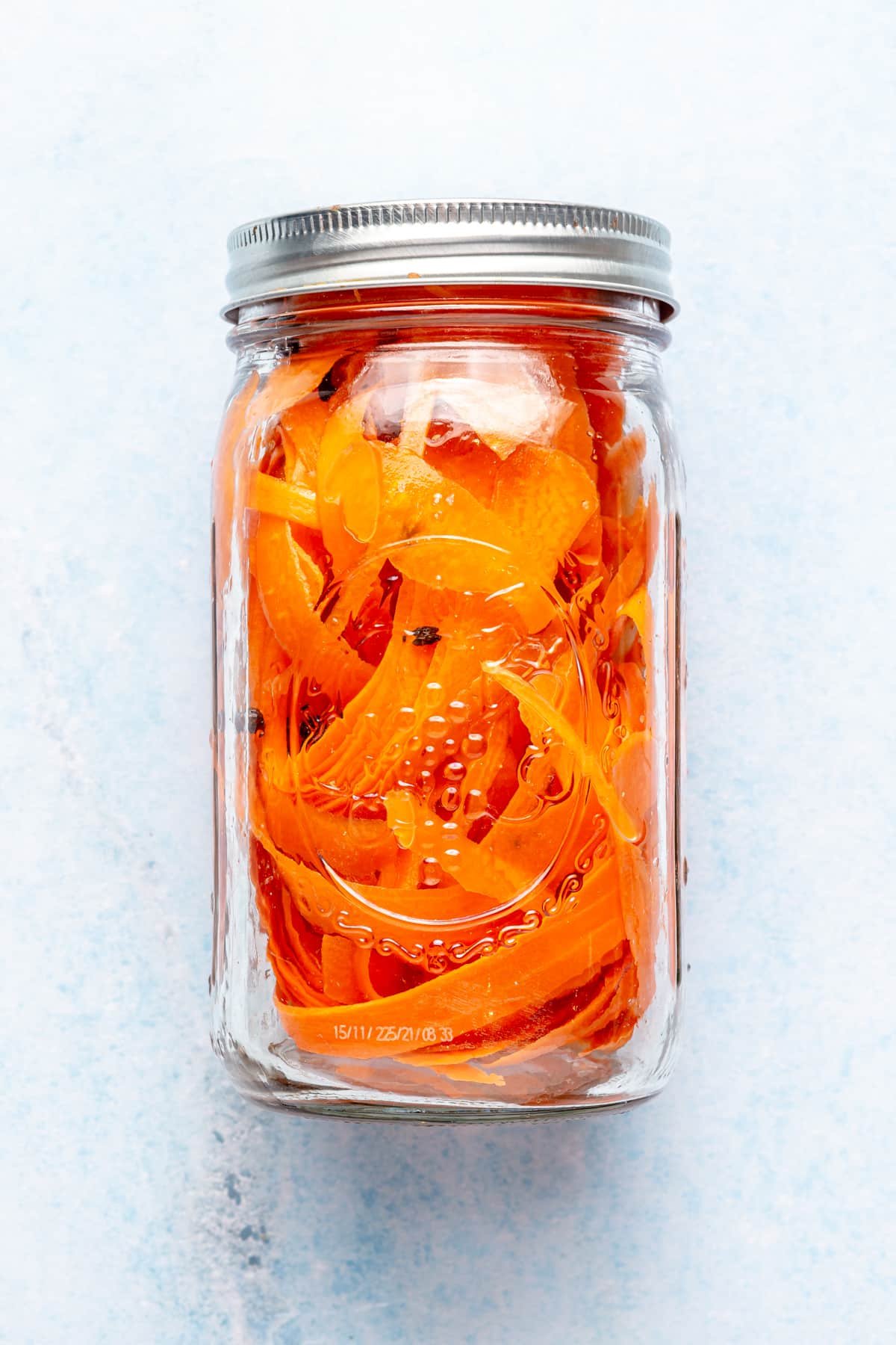 Ribboned carrots pickling in a large mason jar.