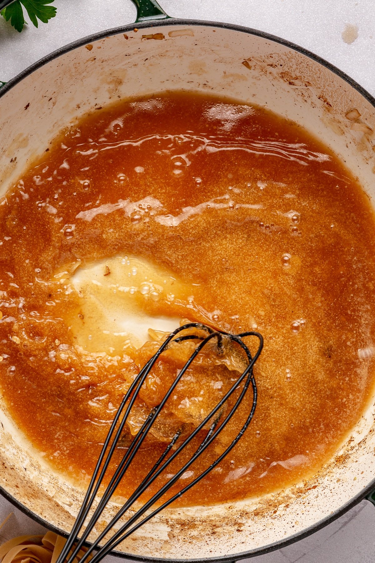 A person whisking the ingredients for beef stroganoff gravy in a pan.