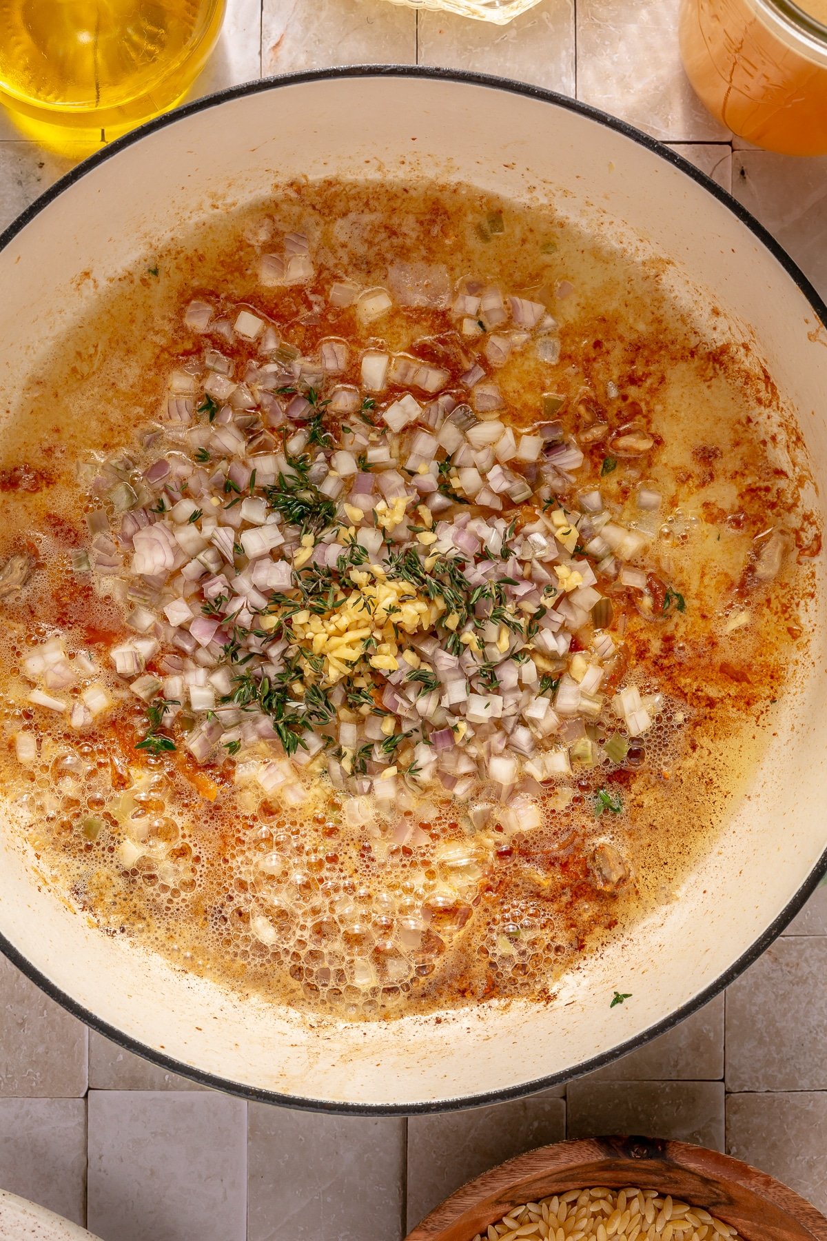 Shallots, garlic, and thyme sizzling in butter in a large enameled cast iron pot.