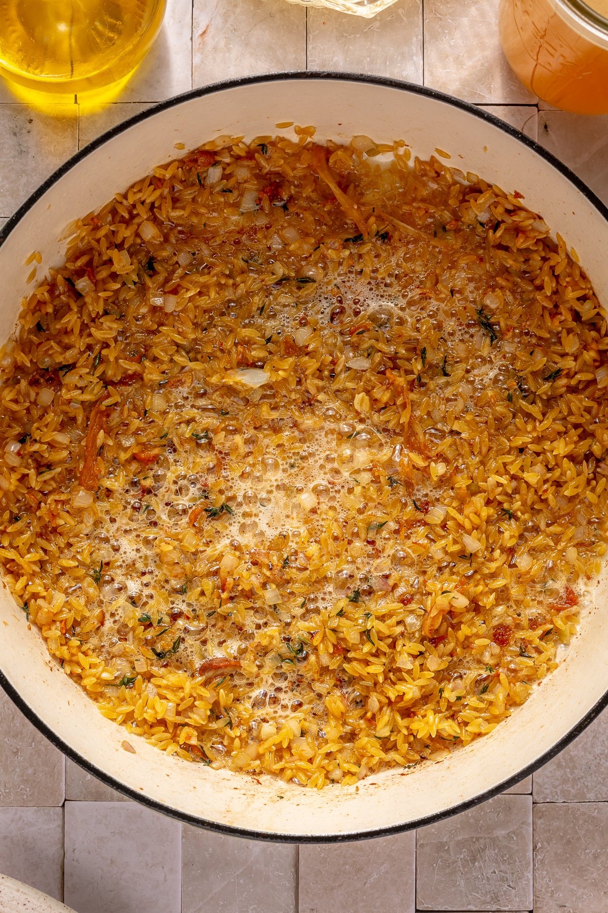 Lemon chicken orzo soup cooking in an enameled cast iron pot.