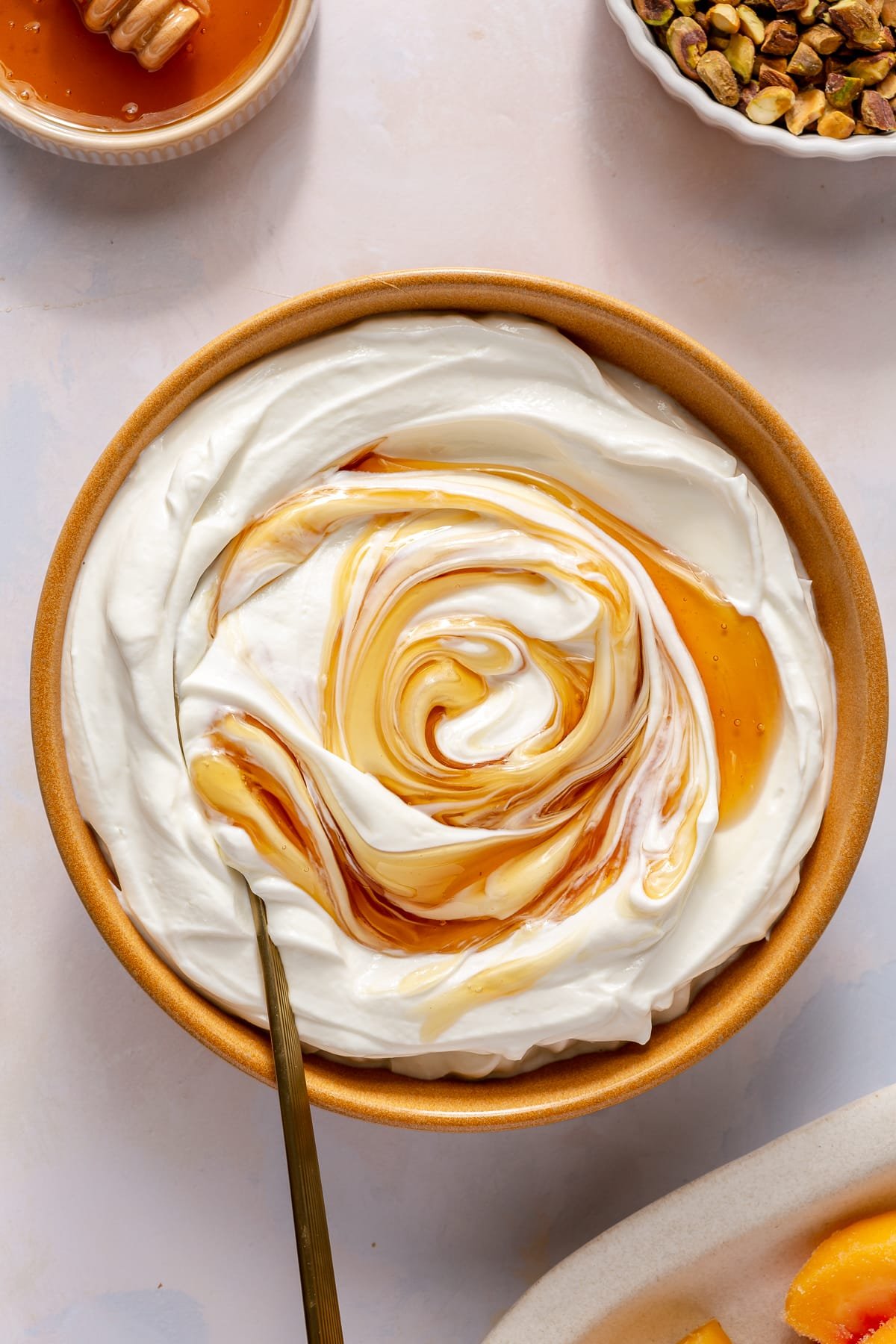 A large bowl of yogurt with honey being stirred into it.