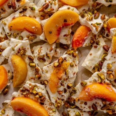 Peaches and cream frozen yogurt bark sitting in a parchment paper lined baking sheet.