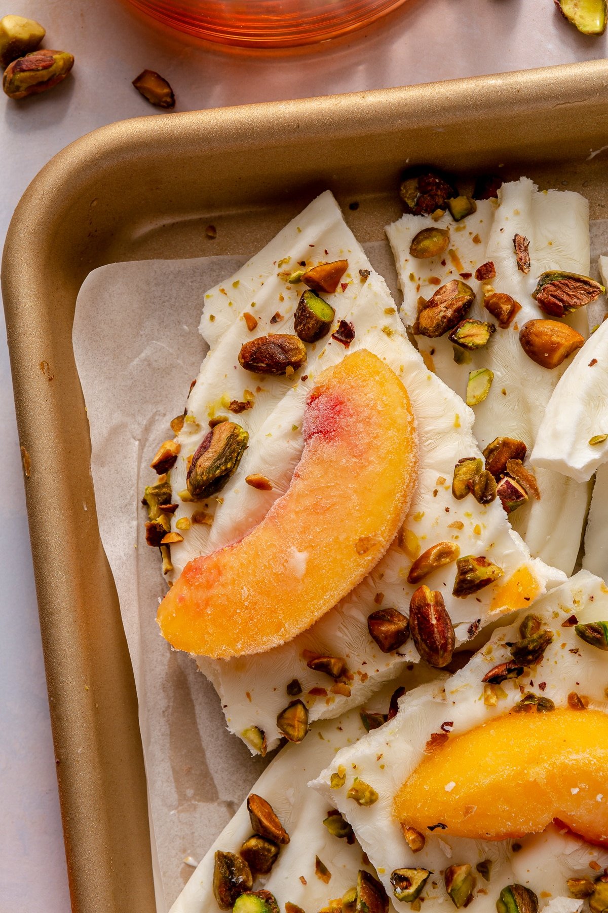 Peaches and cream frozen yogurt bark sitting in a parchment paper lined baking sheet.