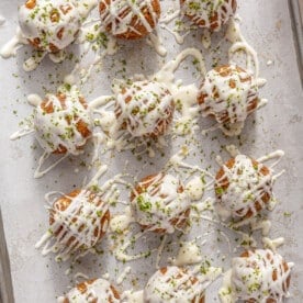 Key Lime Pie energy balls drizzled with white chocolate on a parchment paper lined baking sheet.