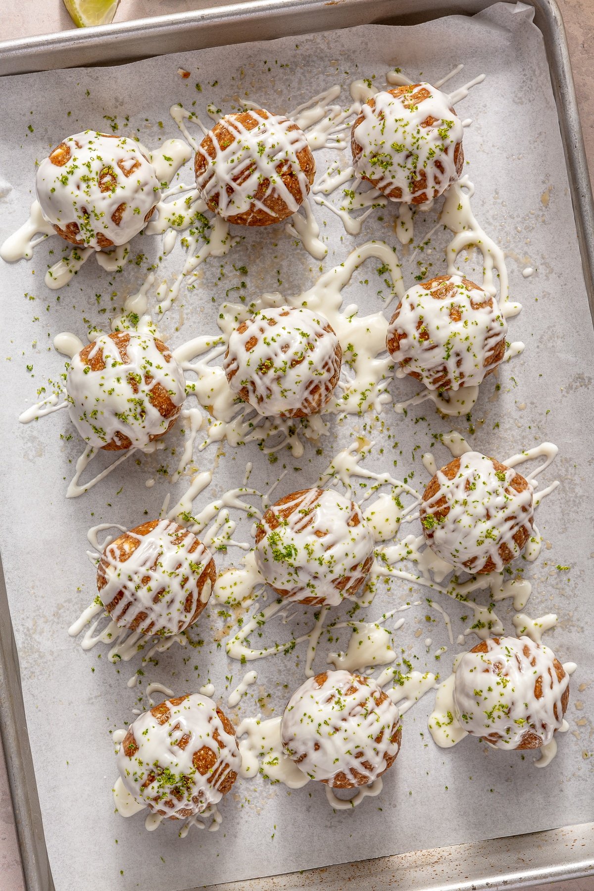 Key Lime Pie energy balls drizzled with white chocolate on a parchment paper lined baking sheet.