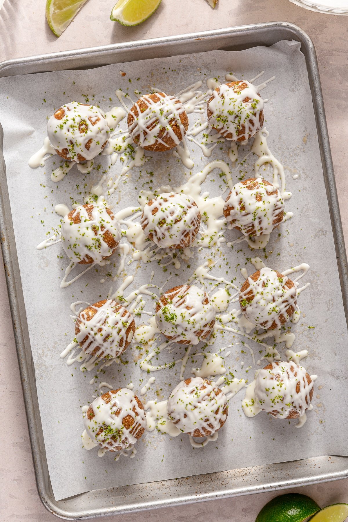 Key Lime Pie energy balls drizzled with white chocolate on a parchment paper lined baking sheet.