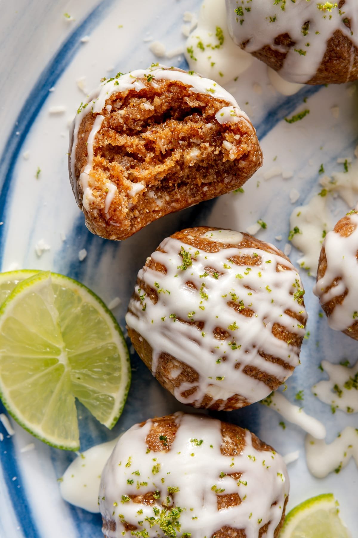 Key Lime Pie energy balls sitting on a blue and white plate next to a cut lime.