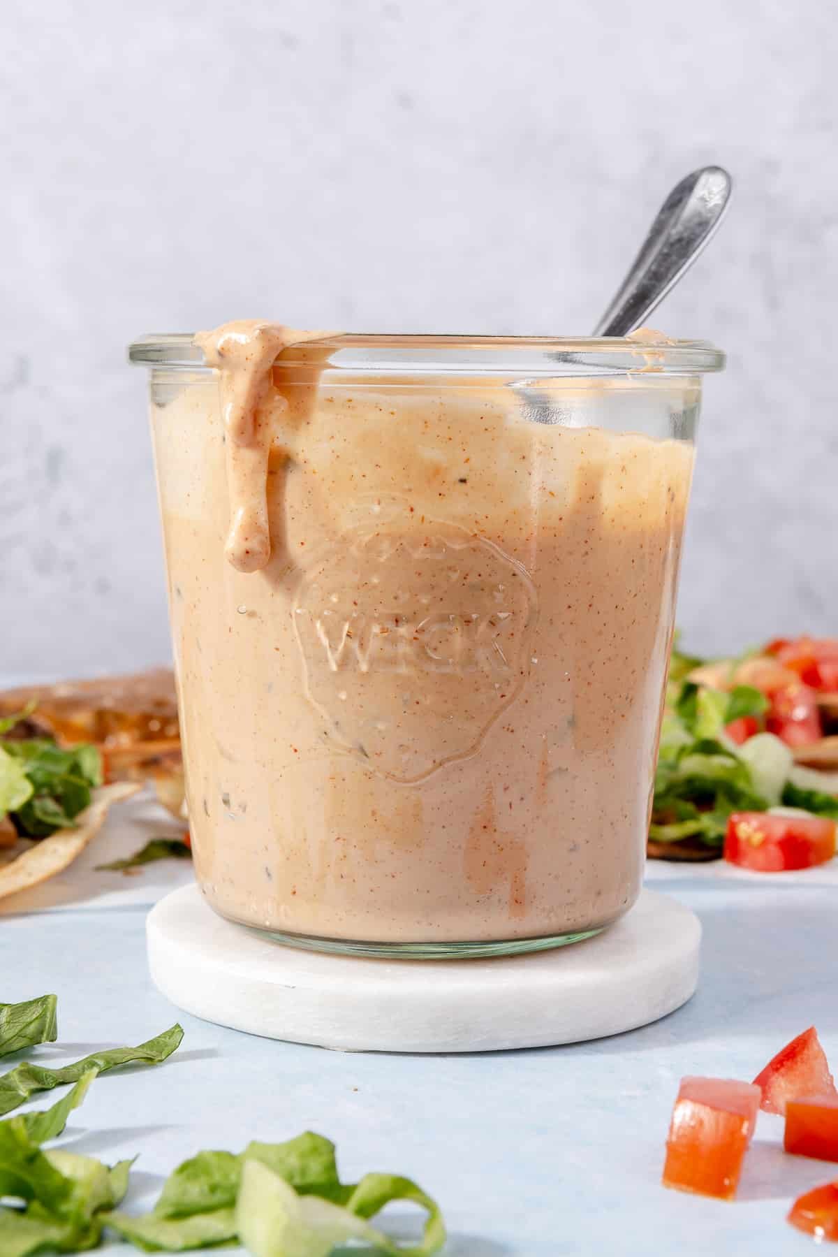 A jar of burger sauce surrounded by smash burger taco toppings.