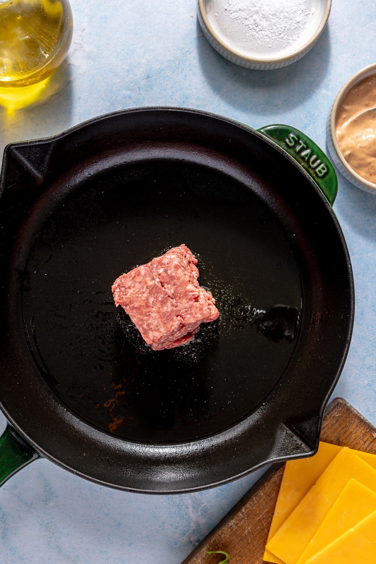 A small portion of raw ground beef on a cast iron skillet.