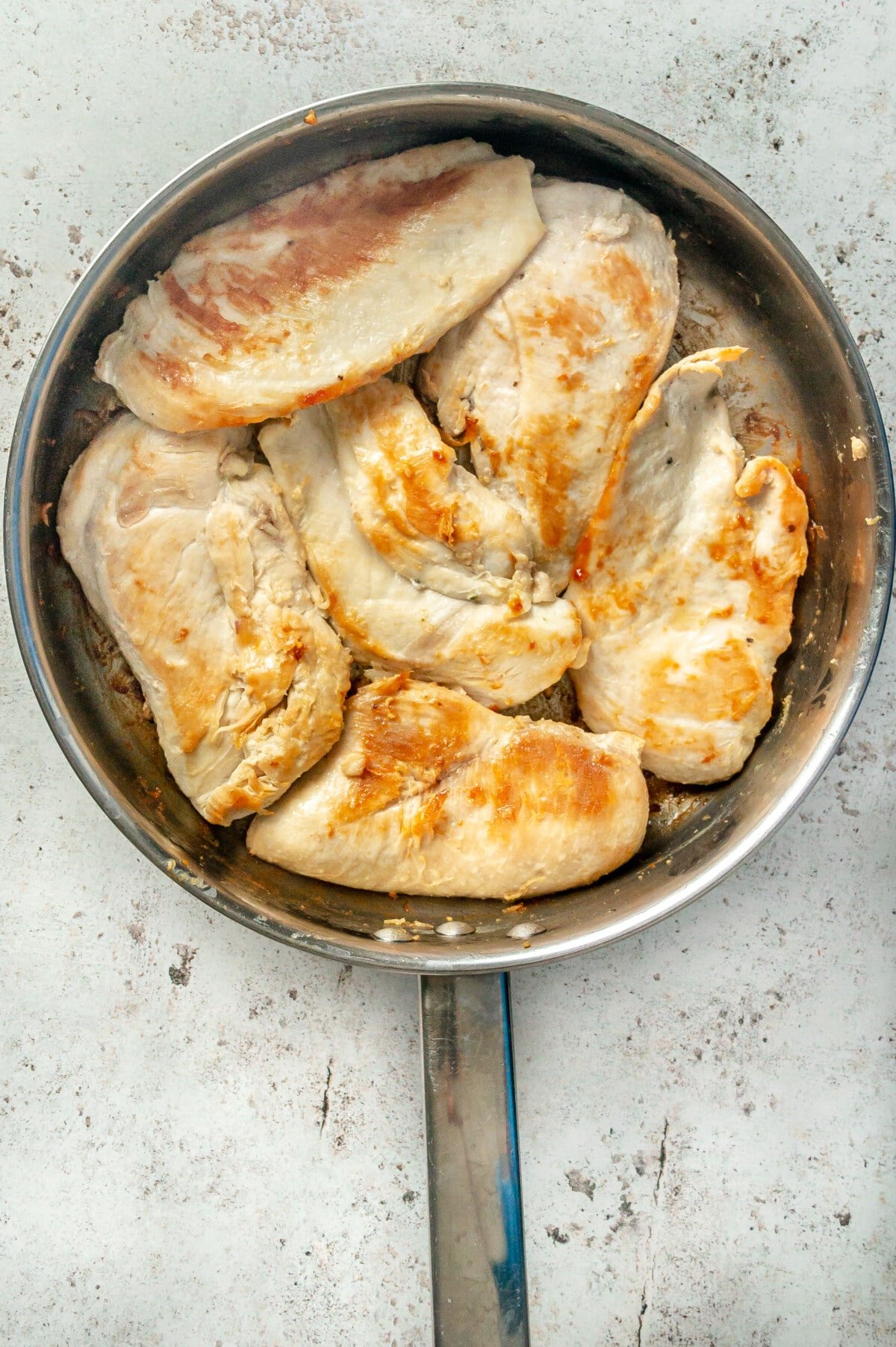 Seared chicken breasts in a stainless steel skillet.