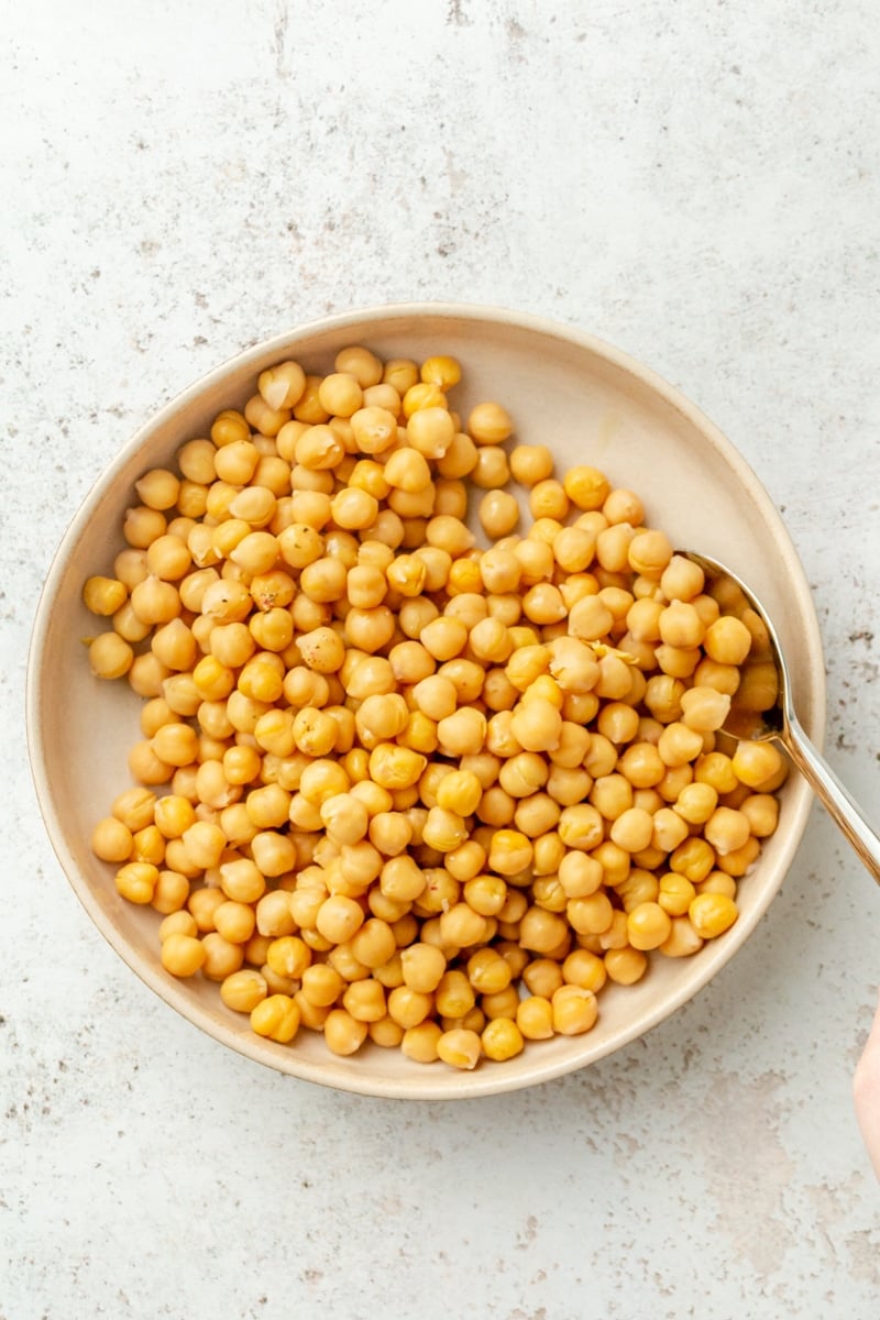 Chickpeas sit on a cream colored plate.