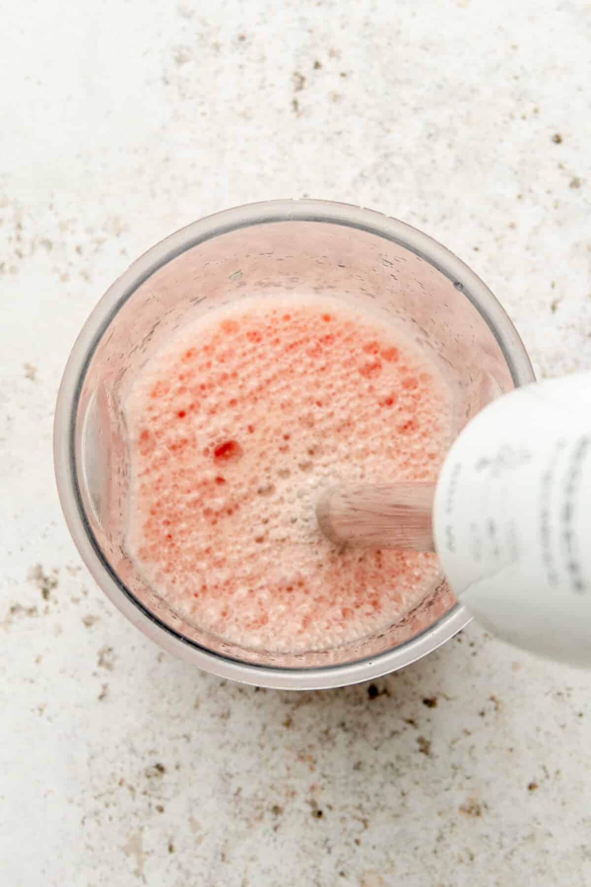 Watermelon and lime juice are blended in a beaker on a light grey surface.
