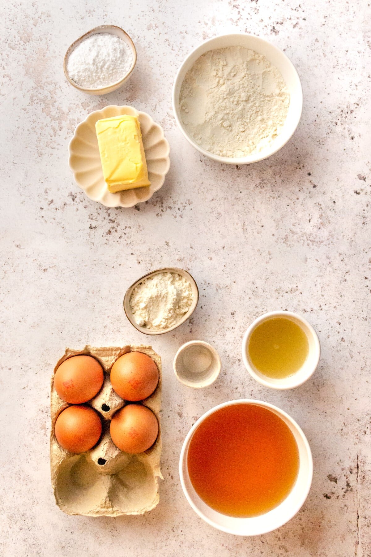 Ingredients for lemon bars sit in a variety of bowls on a concrete surface.