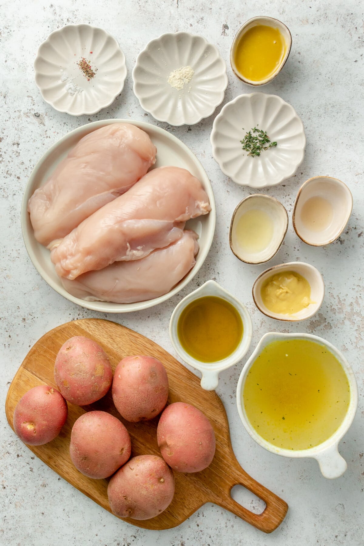 Ingredients for Honey mustard chicken dish laid out in a series of small plates and bowls, all on a white background.