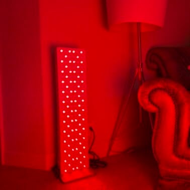 A large Joovv red light panel turned on in a dark room.