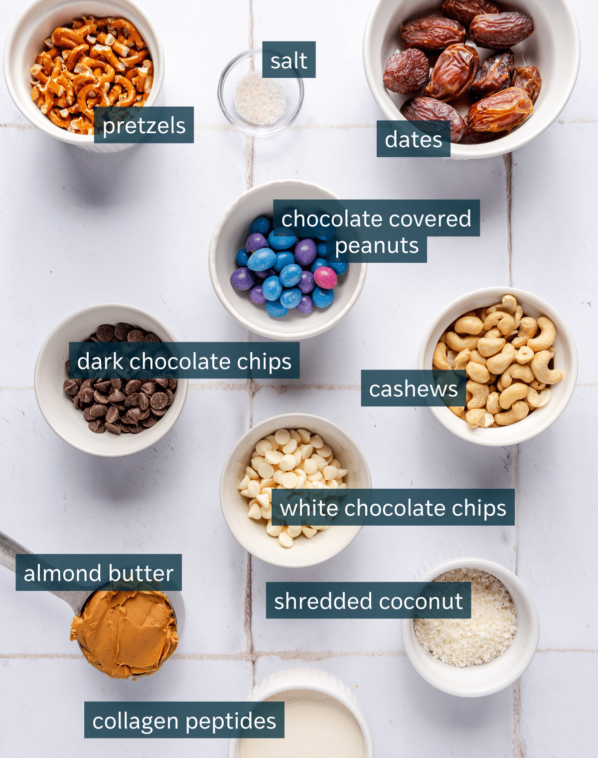 All of the ingredients for kitchen sink energy balls in small bowls on a tile counter.