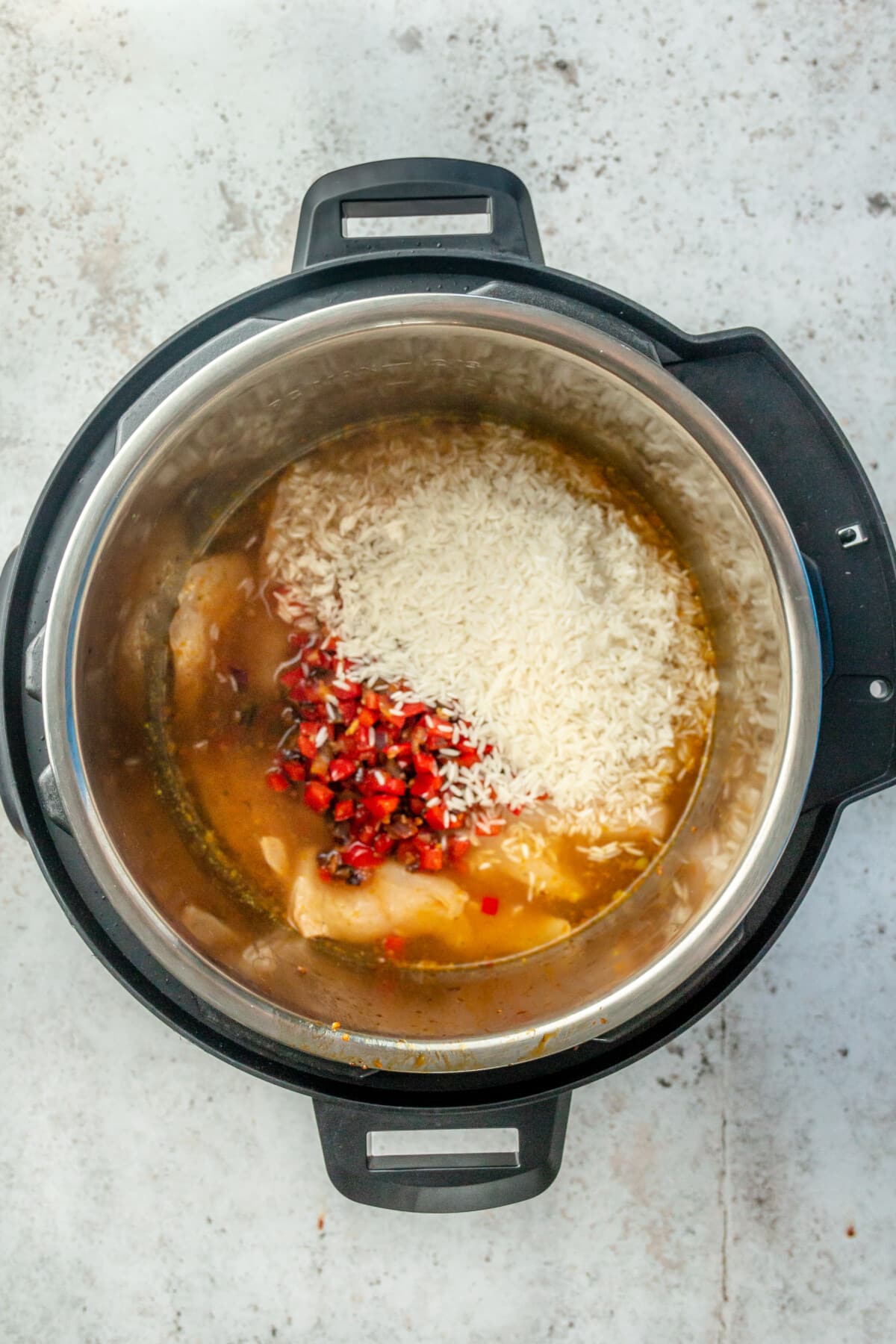 A variety of ingredients have been placed into the instant pot with the chicken.