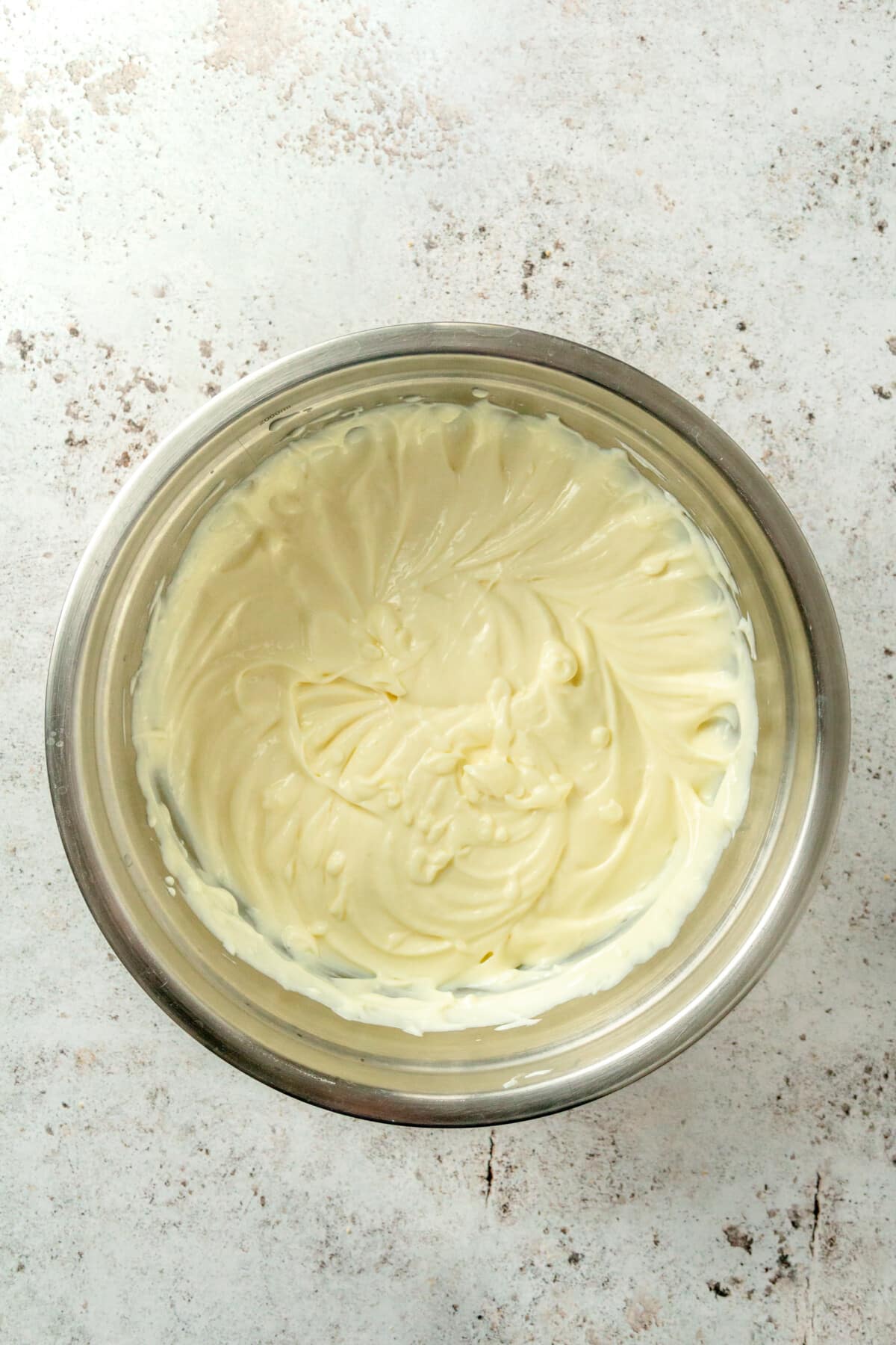 A thick creamy mixture sits in a metal mixing bowl.