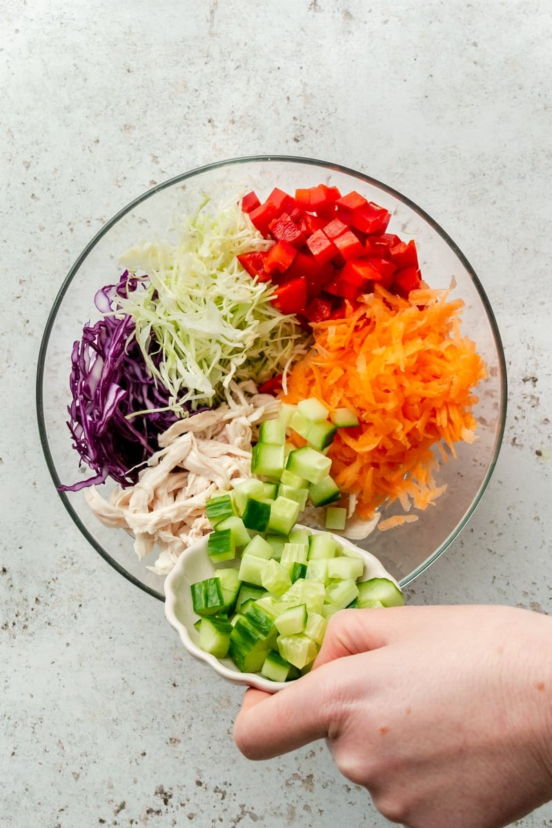 Chopped veggies are shown being poured into a large glass mixing bowl.