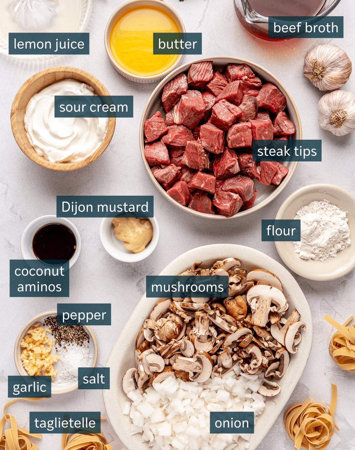 All of the ingredients for gluten free beef stroganoff in bowls on a marble surface.