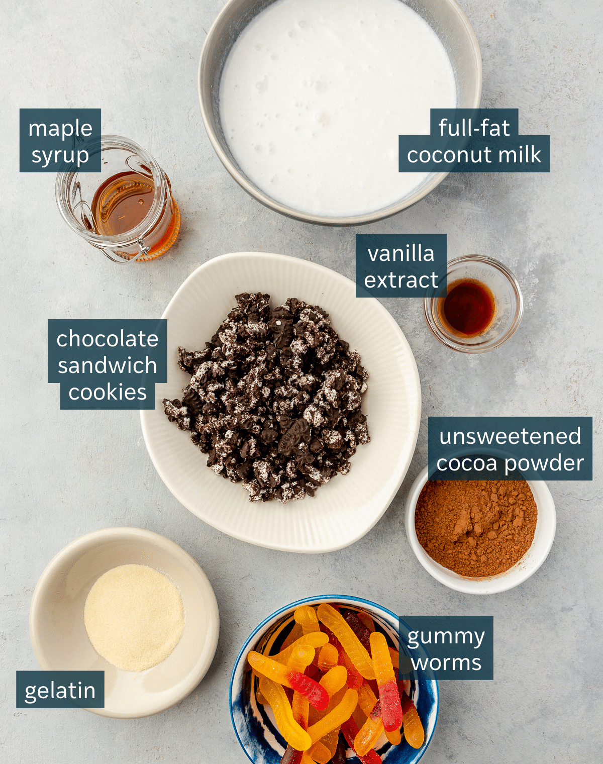 All of the ingredients needed to make dirt worm pudding in different sized vessels on a gray surface.