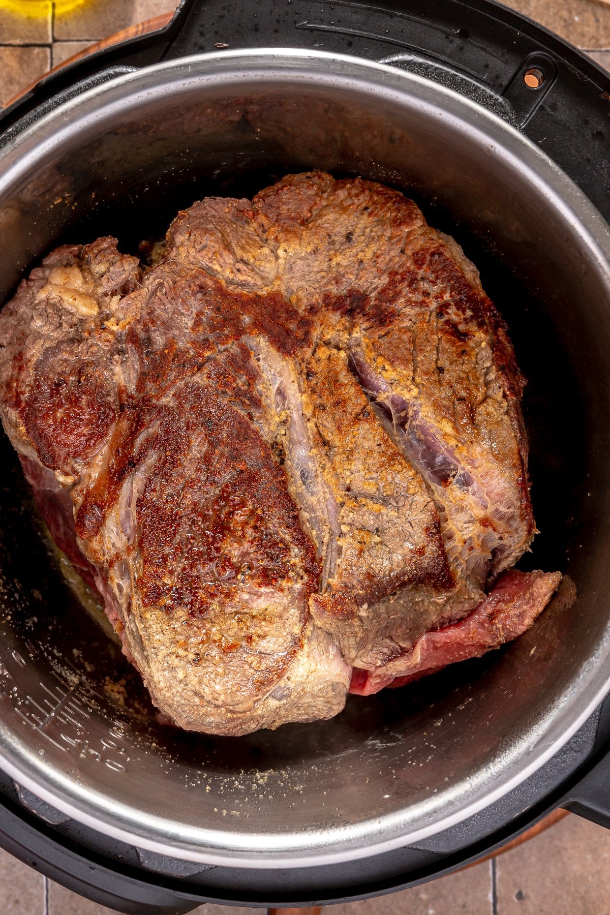 A large seared chuck roast in an Instant Pot.