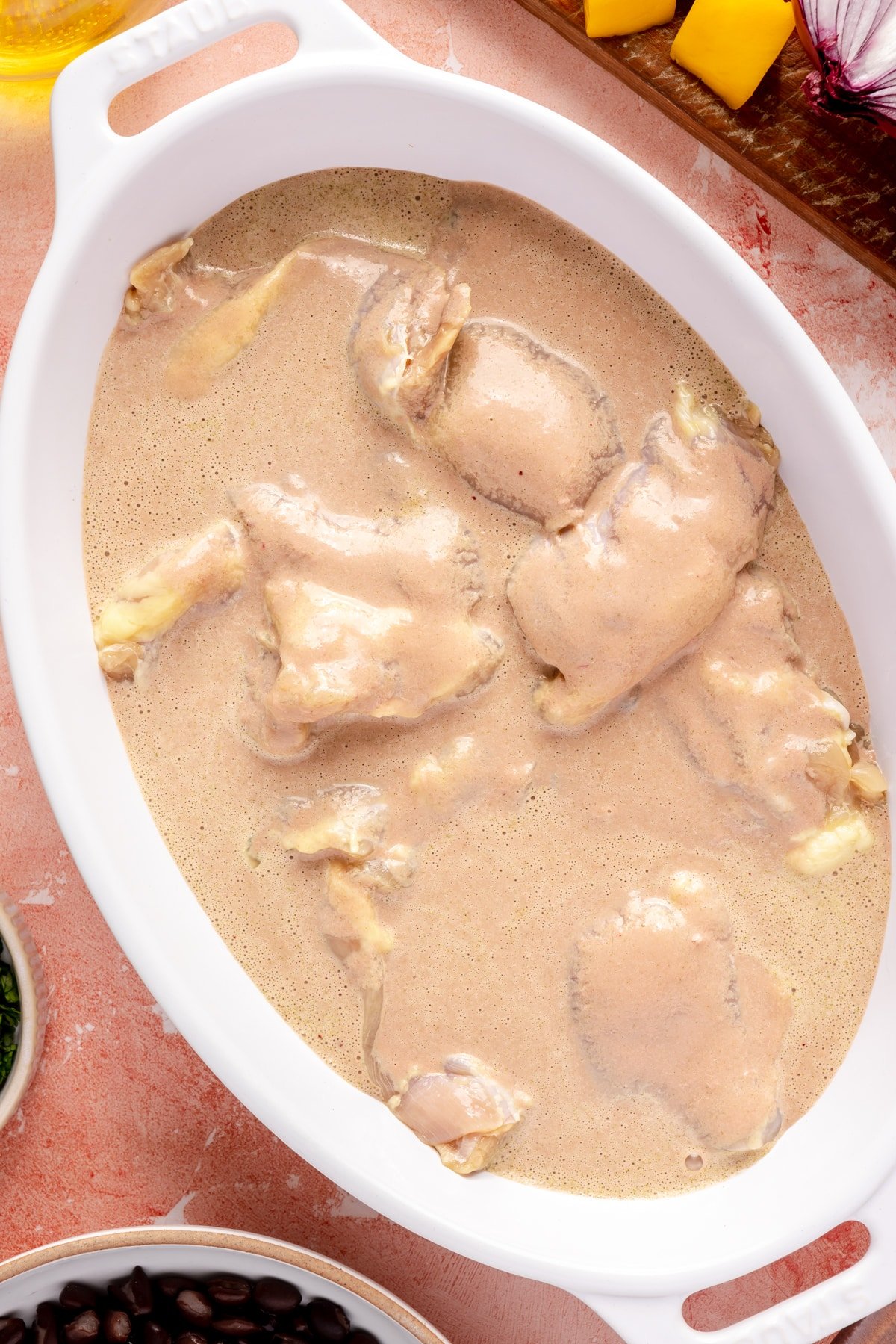 Raw chicken thighs being marinated in Mojo sauce.