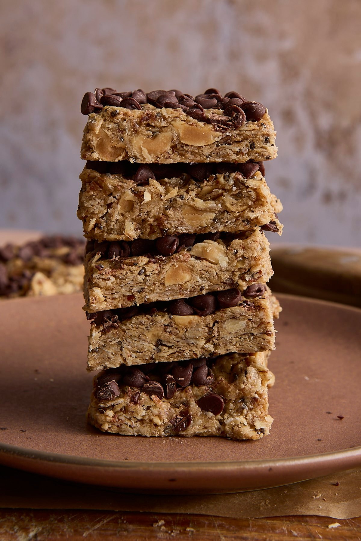 5 high protein and fiber bars stacked on a brown plate.