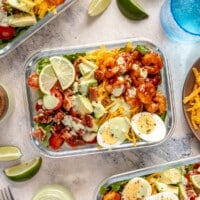 A glass meal prep container filled with spicy shrimp cobb salad.