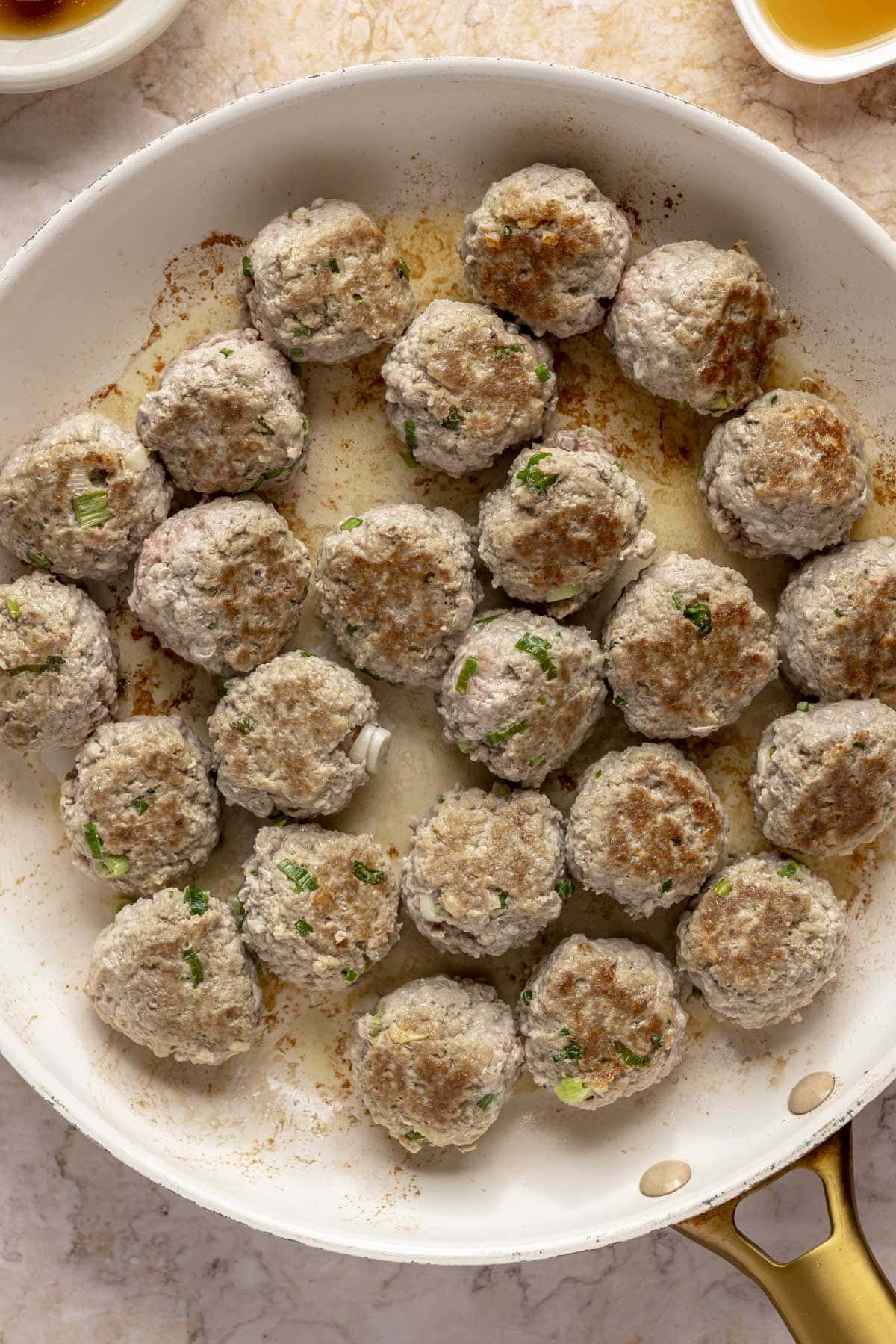 Turkey meatballs searing on a skillet.