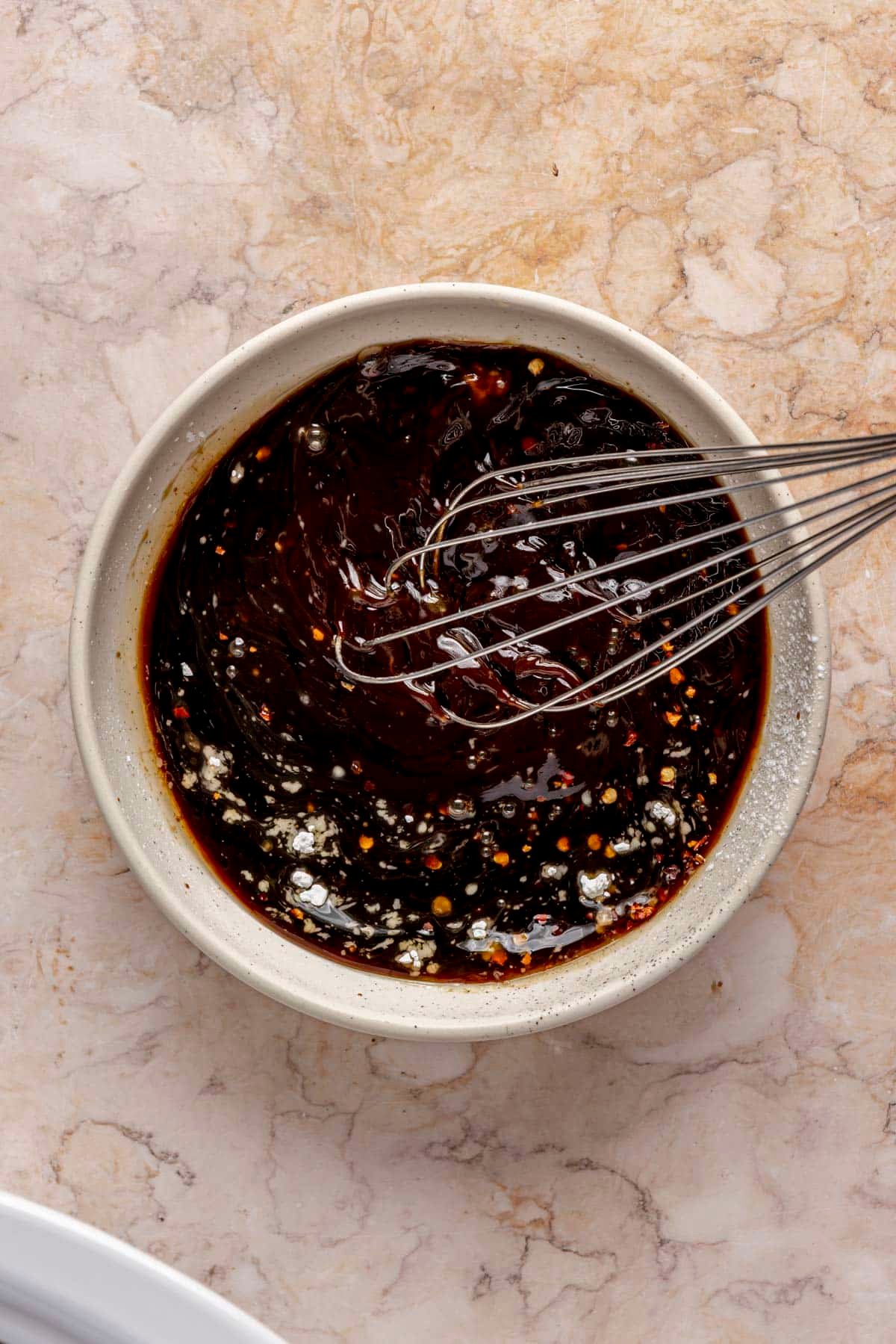 A person whisking together a small bowl of teriyaki sauce.