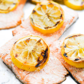 Grilled salmon filets topped with grilled lemon slices.