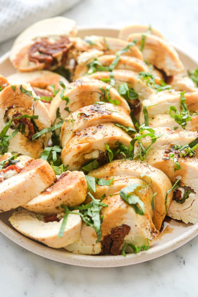 Sliced sun dried tomato chicken breast topped with thinly sliced basil leaves and drizzled with balsamic vinegar.