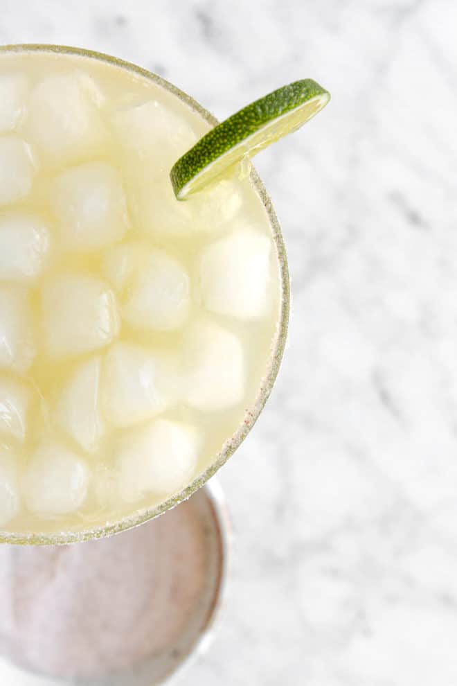 Top down view of margarita on the rocks with slice of lime on the rim.