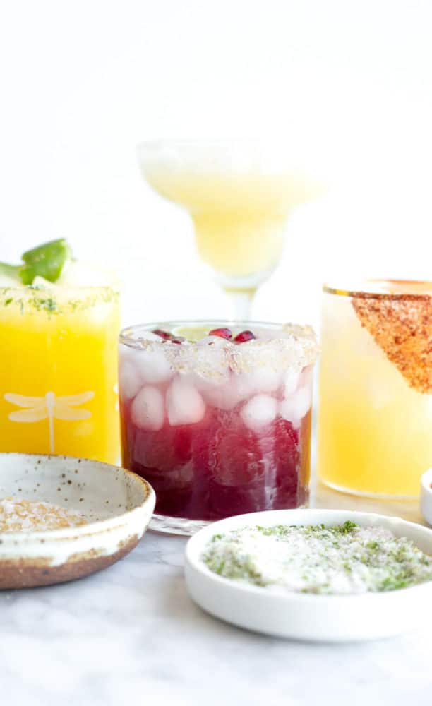 Margaritas and margarita salt in various glasses and bowls.