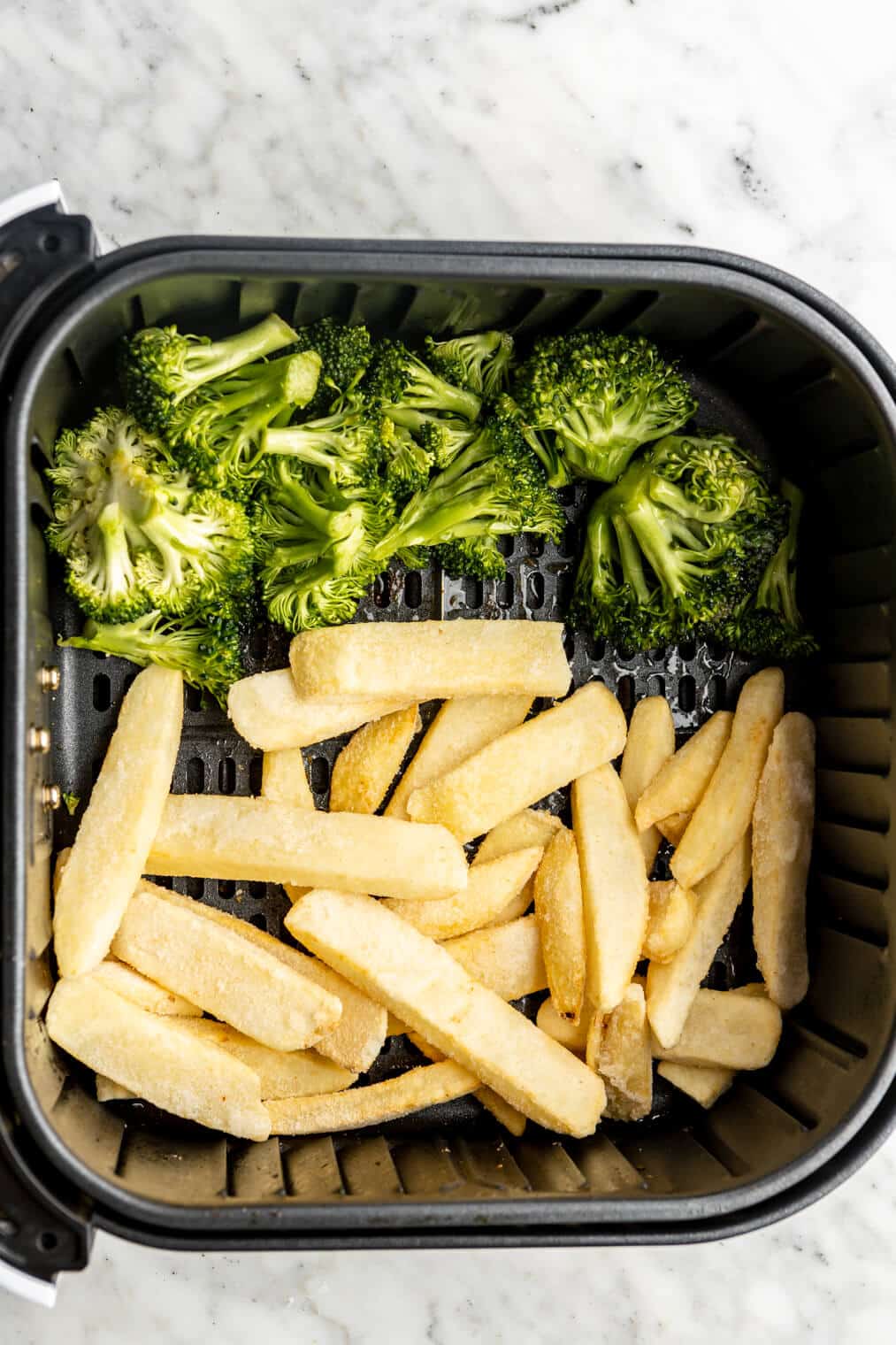 Broccoli and French fries in the air fryer basket.