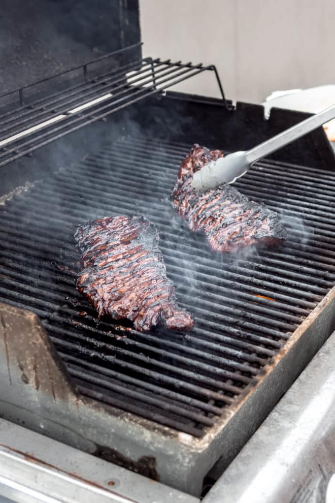 Skirt steak side by side being flipped over on the grill.