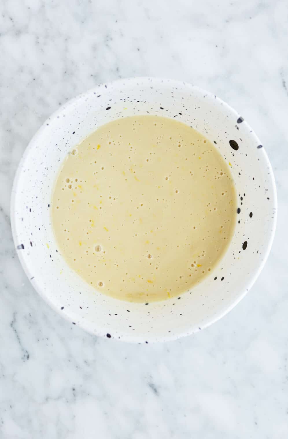 Custard ingredients blended in a black and white speckled bowl.