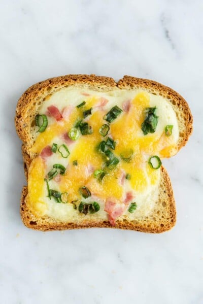 Ham, cheese, and scallion yogurt toast on a grey and white marble surface.